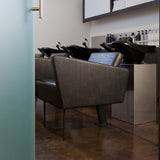 Detailed picture of Facet Wash backwash unit including brown upholstered chair with black legs and black shampoo bowls.