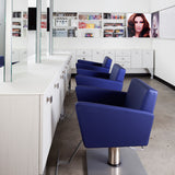 Shown in blue synthetic leather with a silver foot rest and square pump base in a three styling station configuration.